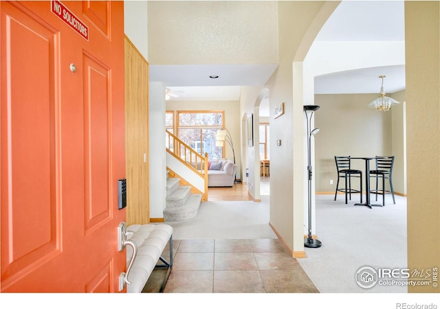 carpeted entryway featuring ceiling fan with notable chandelier