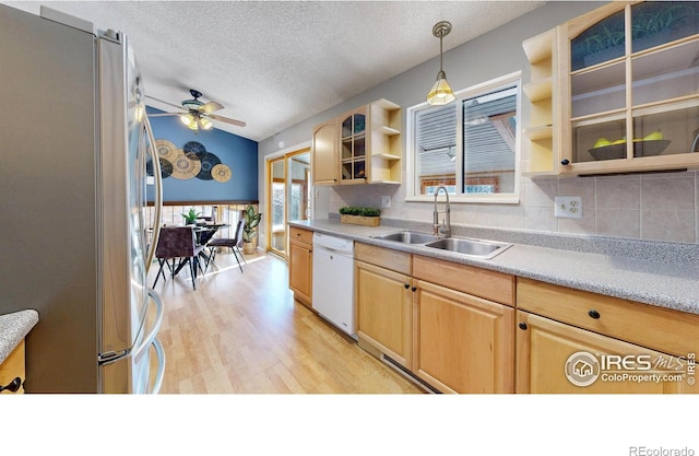 kitchen featuring pendant lighting, sink, light hardwood / wood-style flooring, stainless steel refrigerator, and dishwasher