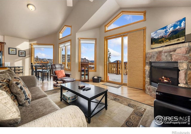 living room featuring vaulted ceiling, a fireplace, and light hardwood / wood-style floors