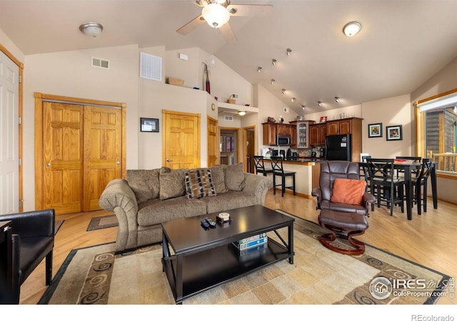 living room with ceiling fan, high vaulted ceiling, and light hardwood / wood-style flooring