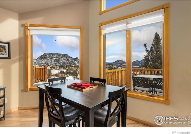 dining area with vaulted ceiling, a mountain view, a healthy amount of sunlight, and light hardwood / wood-style floors