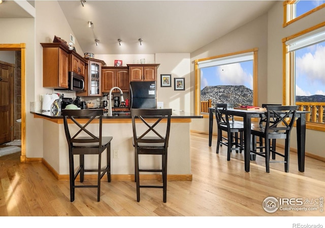 kitchen featuring black fridge, a breakfast bar, a mountain view, and light hardwood / wood-style flooring