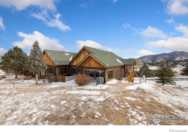 snow covered rear of property with a mountain view and central AC