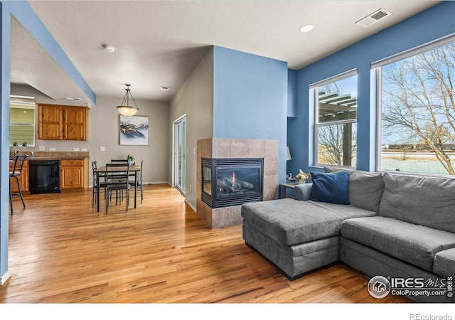 living room featuring a tiled fireplace and light hardwood / wood-style floors