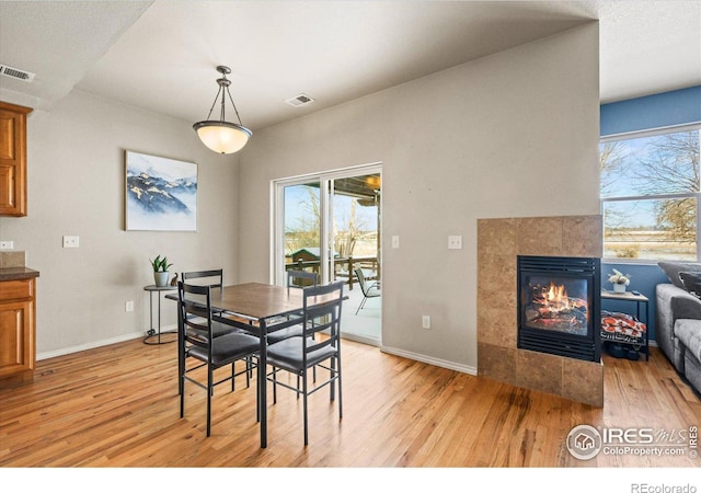 dining room with a tile fireplace and light hardwood / wood-style flooring