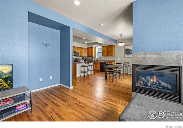 living room with a tiled fireplace, sink, and hardwood / wood-style floors