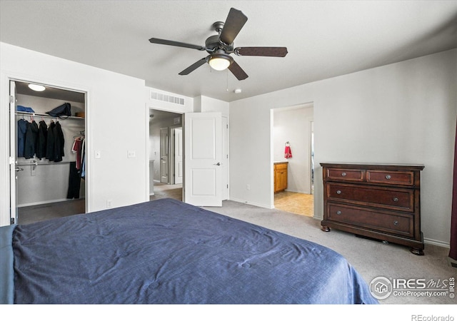 carpeted bedroom with ceiling fan, ensuite bathroom, a closet, and a walk in closet