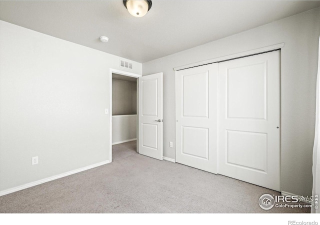 unfurnished bedroom with light colored carpet and a closet