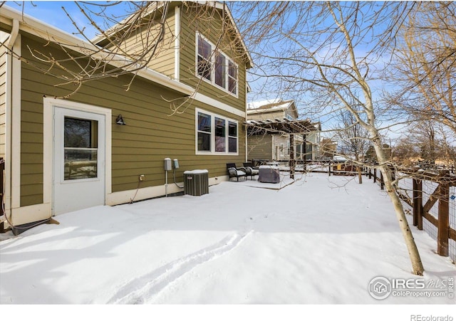 snow covered property with central AC unit and a pergola