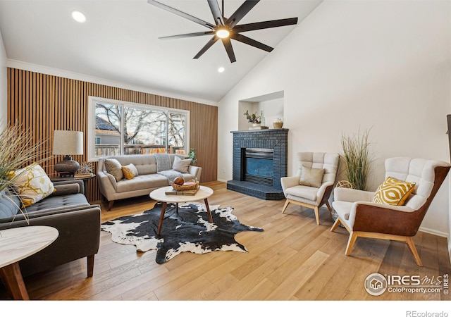 living room featuring hardwood / wood-style flooring, a fireplace, high vaulted ceiling, and ceiling fan