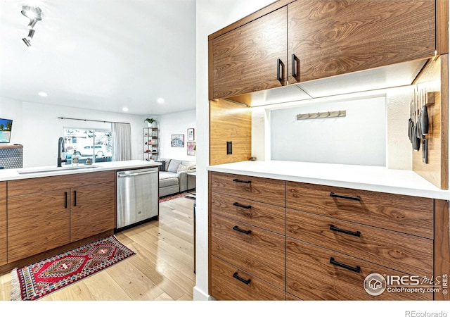 kitchen with dishwasher, sink, track lighting, and light hardwood / wood-style flooring