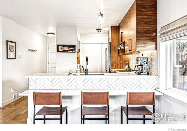 kitchen with sink, dark wood-type flooring, a breakfast bar, and a healthy amount of sunlight