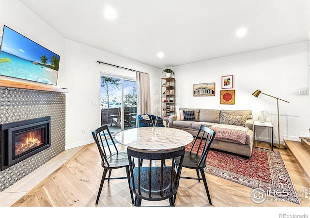 dining area with a tile fireplace and light hardwood / wood-style floors