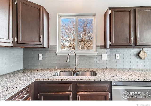 kitchen featuring tasteful backsplash, dishwasher, sink, light stone countertops, and dark brown cabinets