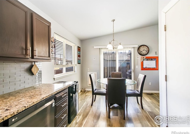 dining area with an inviting chandelier, vaulted ceiling, and light hardwood / wood-style flooring