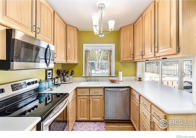 kitchen with stainless steel appliances, hanging light fixtures, sink, and light brown cabinetry