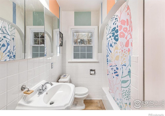 full bathroom featuring tile walls, sink, toilet, and shower / bath combo