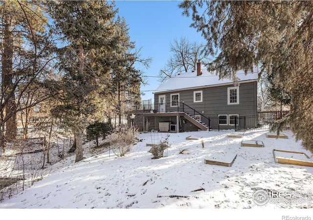 snow covered back of property with a deck