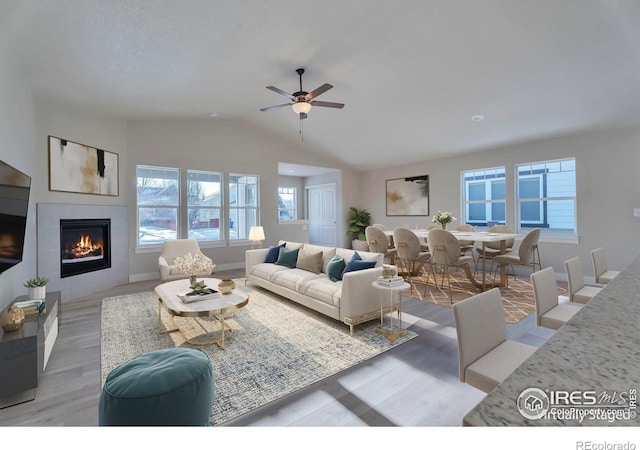 living room featuring ceiling fan, wood-type flooring, a fireplace, and vaulted ceiling