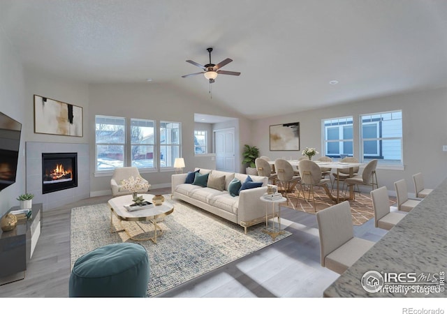 5753 Pintail Way, Frederick, CO 80504 - living room featuring vaulted ceiling, a tile fireplace, light wood-style floors, ceiling fan, and baseboards