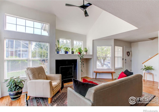 living room featuring ceiling fan, wood-type flooring, and vaulted ceiling