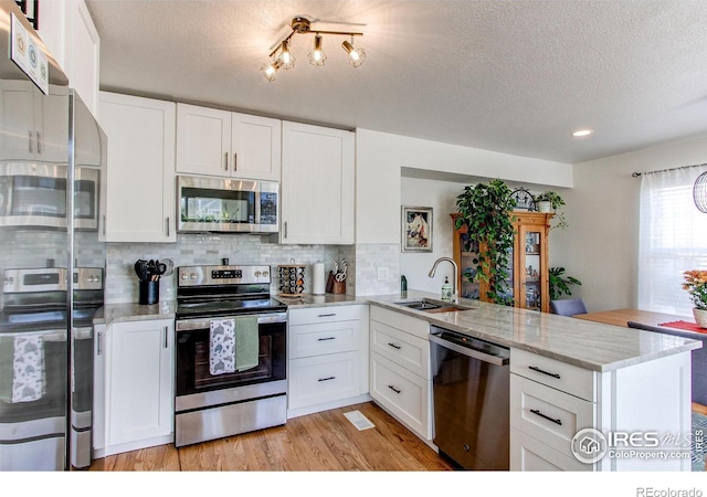 kitchen featuring appliances with stainless steel finishes, white cabinets, and kitchen peninsula