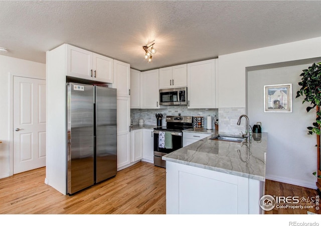 kitchen featuring appliances with stainless steel finishes, sink, white cabinets, and kitchen peninsula