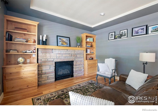 living room featuring a tray ceiling, hardwood / wood-style flooring, and a fireplace