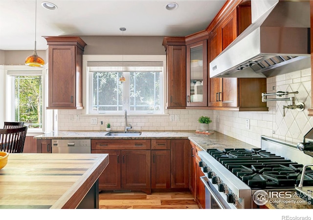 kitchen with sink, wall chimney range hood, decorative backsplash, and decorative light fixtures