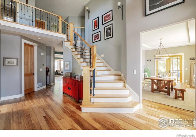 stairs with plenty of natural light, hardwood / wood-style floors, and a high ceiling