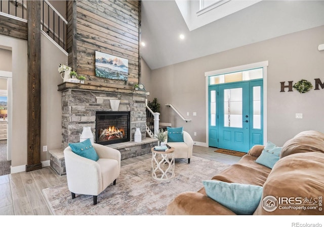 living room with a fireplace, a skylight, and high vaulted ceiling