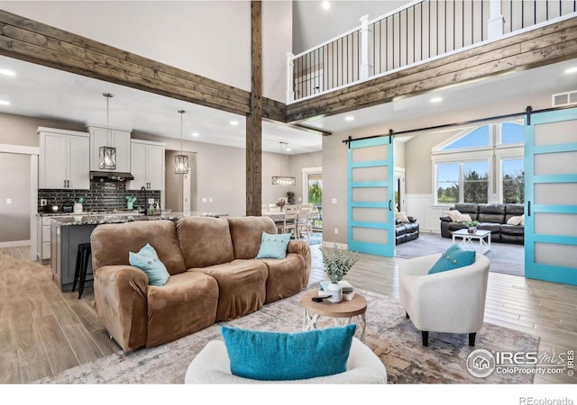 living room featuring a towering ceiling and a barn door