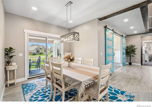 dining area featuring a barn door and light hardwood / wood-style floors