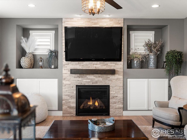 living room with a fireplace, light hardwood / wood-style floors, and ceiling fan