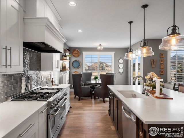 kitchen with appliances with stainless steel finishes, an island with sink, hanging light fixtures, and white cabinets