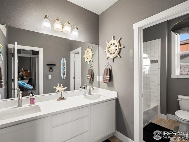 full bathroom featuring tiled shower / bath, vanity, and toilet