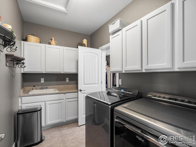 clothes washing area with sink, light tile patterned floors, cabinets, and washer and dryer