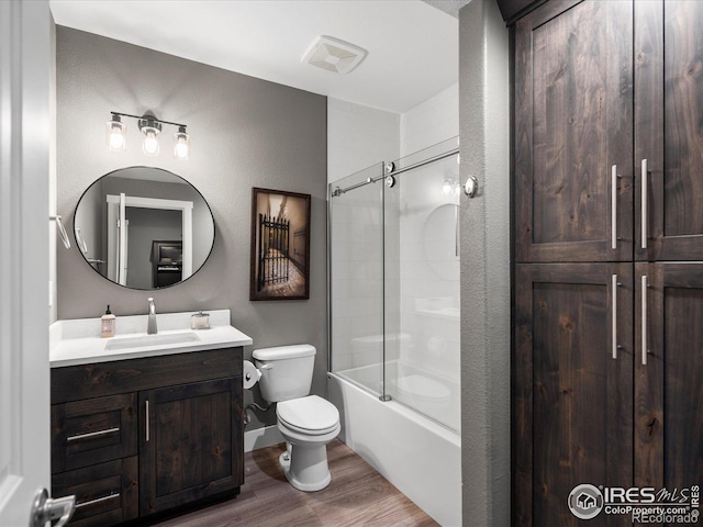 full bathroom featuring bath / shower combo with glass door, hardwood / wood-style floors, vanity, and toilet