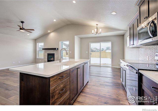 kitchen with sink, tasteful backsplash, appliances with stainless steel finishes, pendant lighting, and a kitchen island with sink