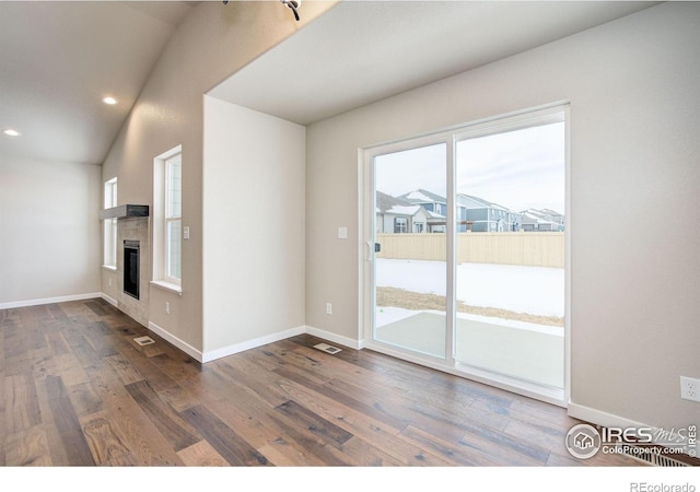 unfurnished living room featuring vaulted ceiling, a fireplace, and dark hardwood / wood-style flooring