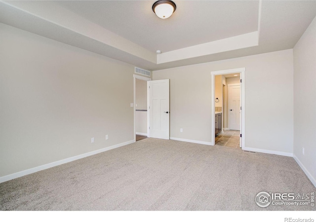 unfurnished bedroom with a tray ceiling and light carpet