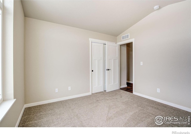 unfurnished bedroom with lofted ceiling and carpet