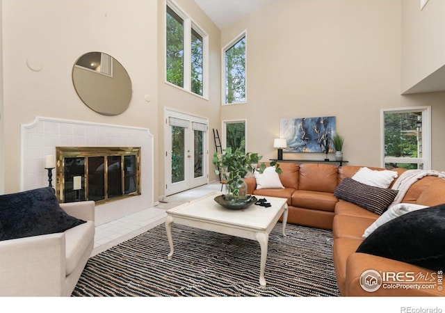 living room with a tiled fireplace and a towering ceiling