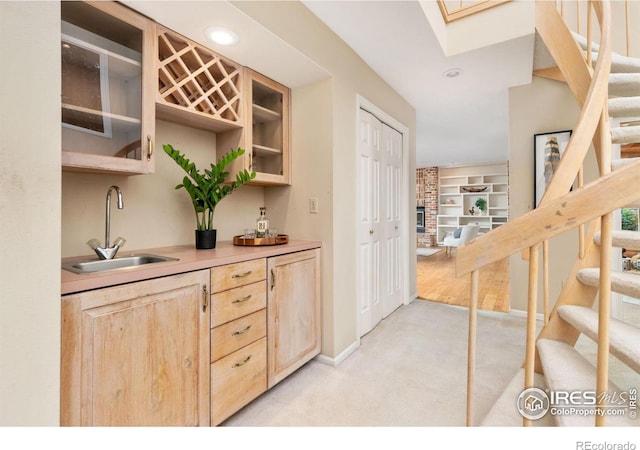 bar featuring light brown cabinetry, sink, a skylight, a brick fireplace, and light colored carpet