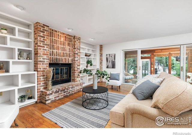 living room featuring built in shelves, a fireplace, and hardwood / wood-style floors