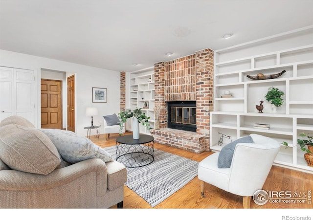 living room featuring hardwood / wood-style flooring and a brick fireplace