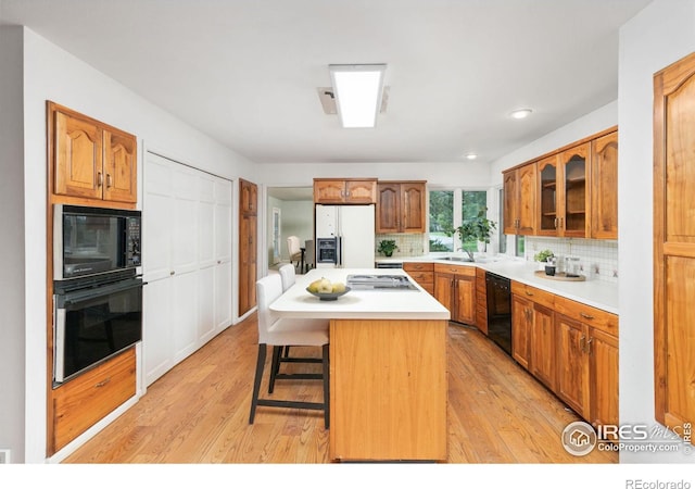 kitchen featuring sink, a kitchen breakfast bar, black appliances, a kitchen island, and decorative backsplash