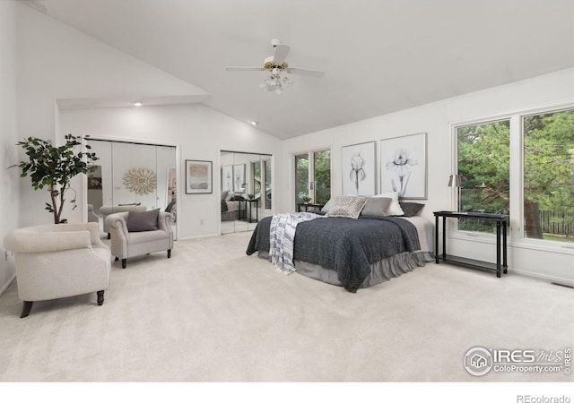 bedroom with multiple windows, ceiling fan, light carpet, and multiple closets