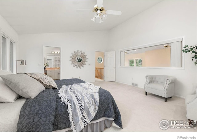 bedroom featuring ensuite bathroom, vaulted ceiling, light colored carpet, and ceiling fan