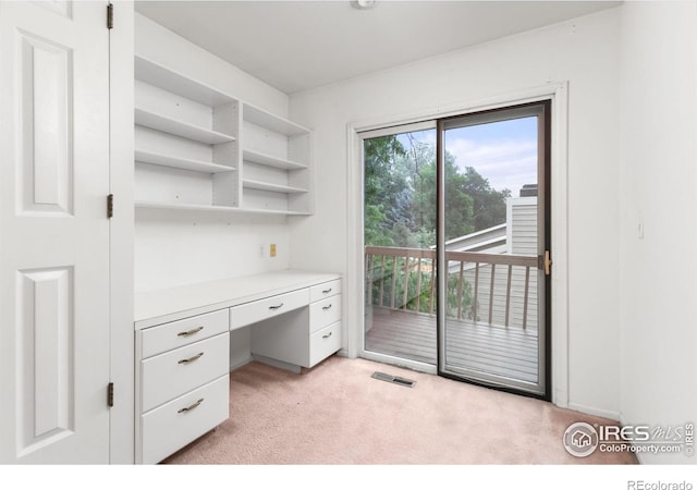 unfurnished office featuring built in desk and light carpet